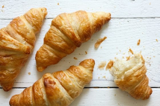 Golden Croissants On Rustic White Wood, From Above.