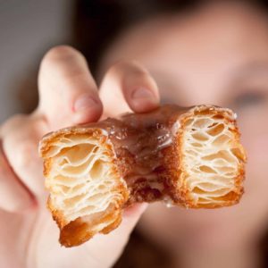 Croissant,And,Doughnut,Mixture,Being,Held,By,A,Girl,Close Up